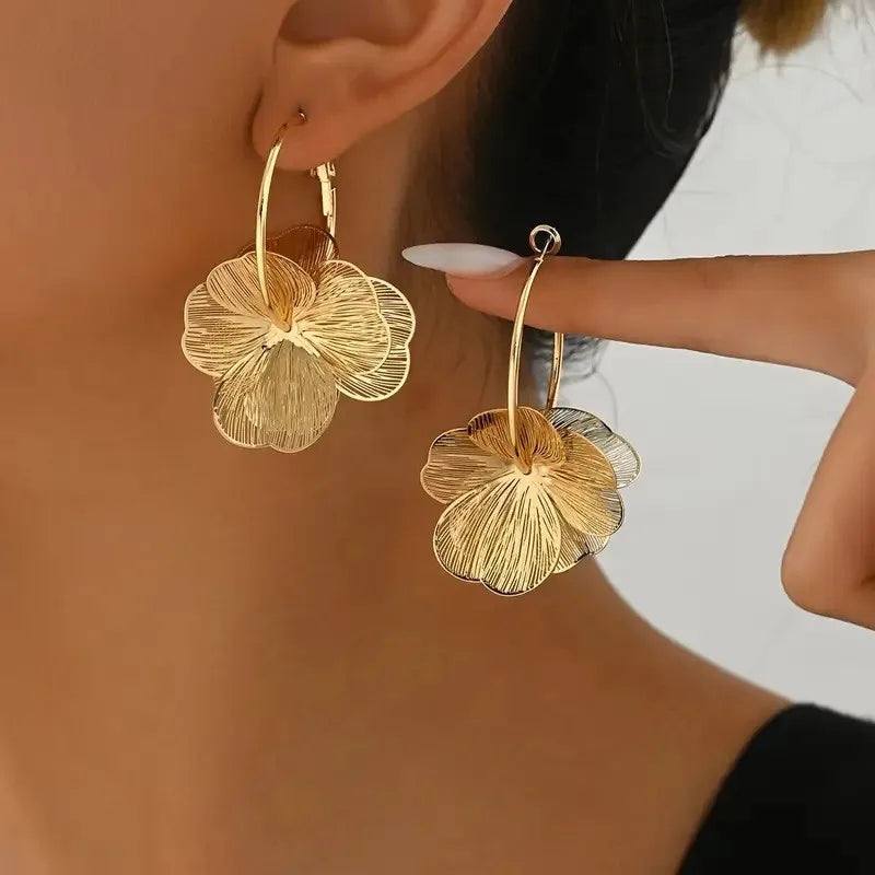 Gold flower hoop earrings with textured petals worn by woman, statement floral dangle earrings jewelry
