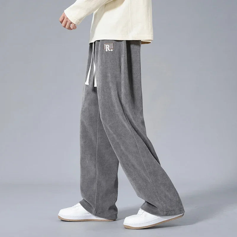 Men's wide-leg gray corduroy drawstring sweatpants with embroidered R patch, paired with white sneakers and cream top