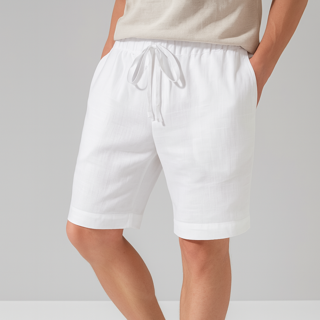 Men's white linen drawstring shorts with elastic waistband, side pockets, and rolled cuffs, paired with a beige top.