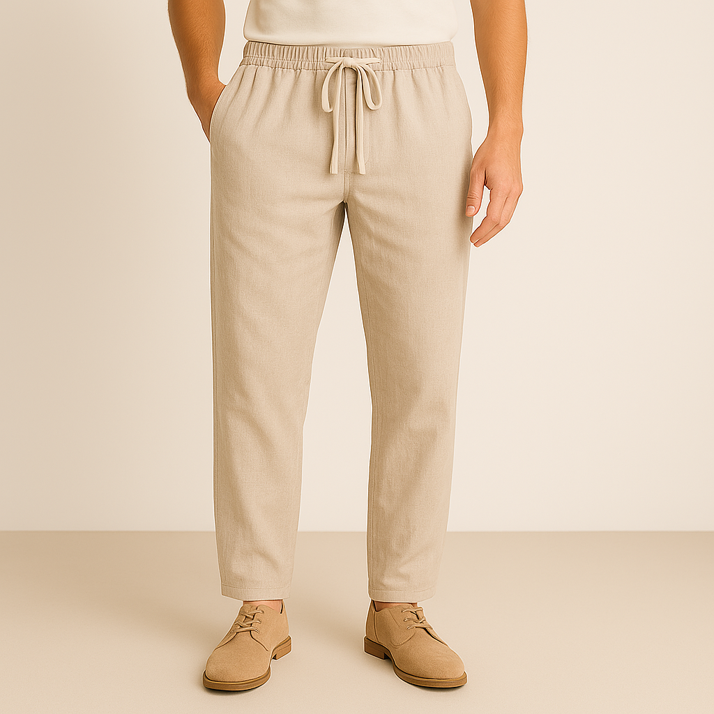 Men's beige linen-cotton drawstring pants with elastic waistband, tapered fit, styled with tan suede oxford shoes.