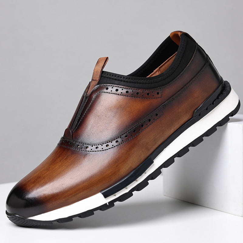 Men's brown leather slip-on loafers with brogue wingtip detail and white rubber sole on gray background