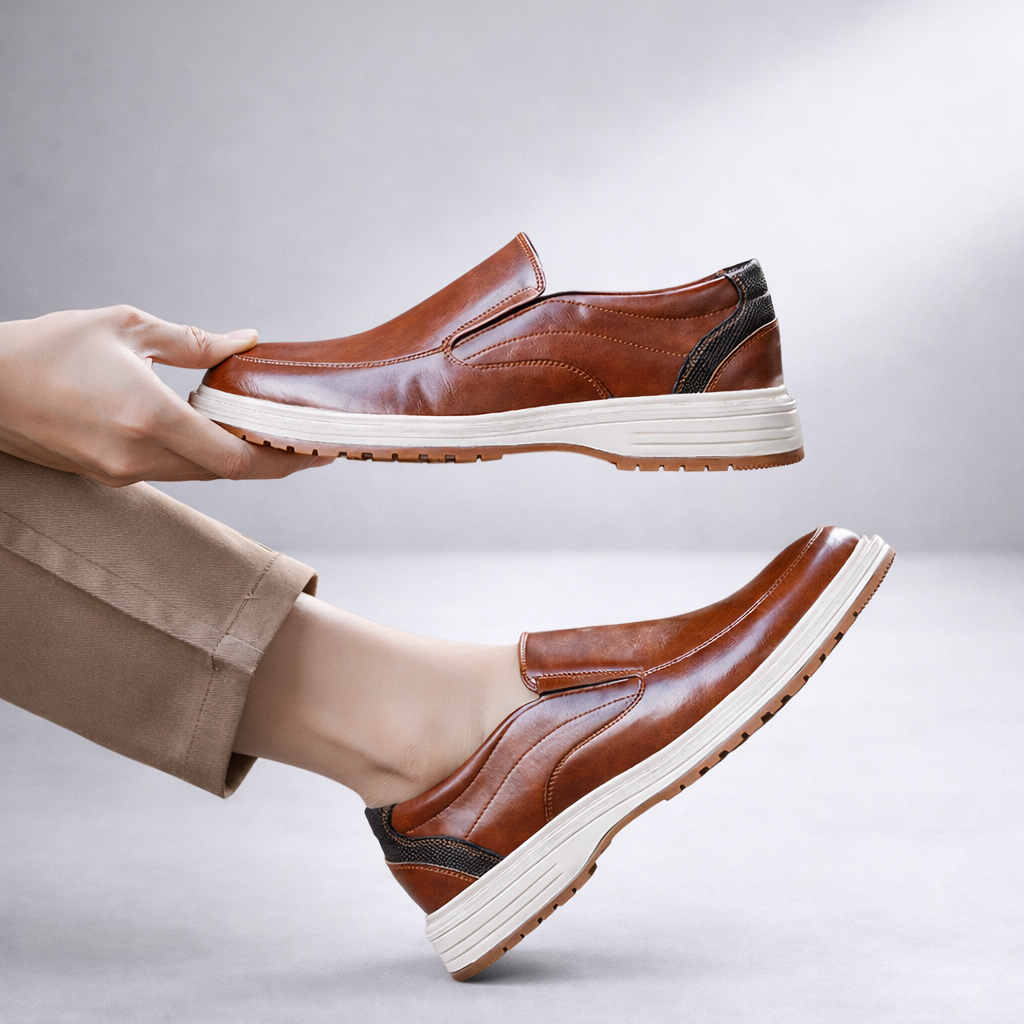 Men's brown leather slip-on loafers with white platform sole and textured heel detail on beige pants