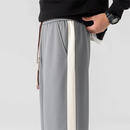 Gray wide-leg men's sweatpants with white side stripe, elastic waistband, drawstring, and side pocket, paired with black sweatshirt