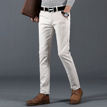 Men's slim-fit white cotton dress pants with black belt styled with striped shirt and brown leather shoes