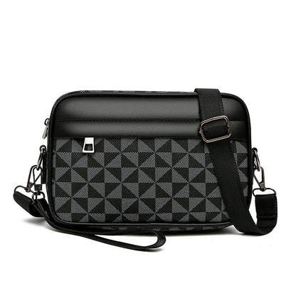 Black and gray geometric checkered crossbody bag with adjustable strap, zip closure, and wrist loop handle