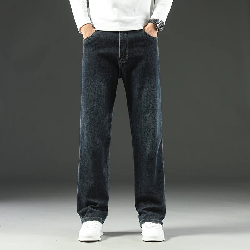 Man wearing dark blue straight leg stretch denim jeans with white sneakers and white sweater, front view.