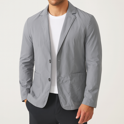 Men's gray nylon two-button blazer jacket with patch pockets, worn open over a white t-shirt with navy pants.