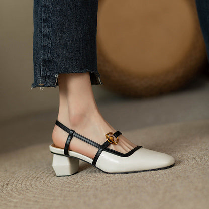 Women's ivory leather block heel slingback sandals with black straps and gold circular buckle, paired with jeans