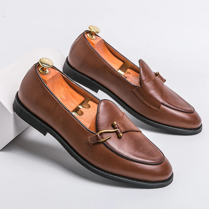 Brown leather men's slip-on loafers with gold metal buckle detail, displayed with cedar shoe trees on white background