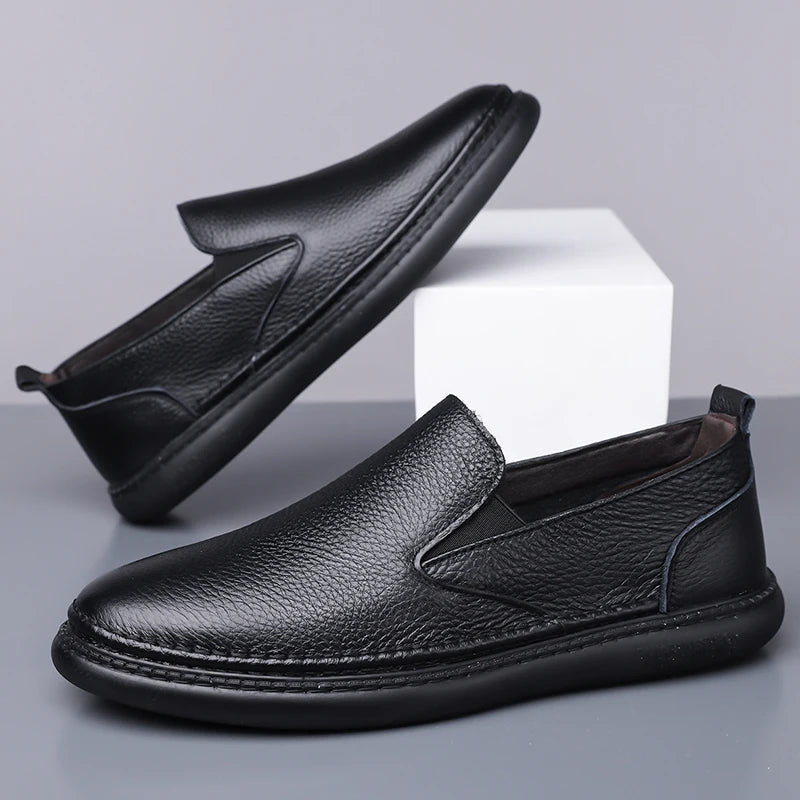 Black men's leather slip-on loafers with pebbled texture, elastic side gussets, and flexible rubber sole, shown in pair.