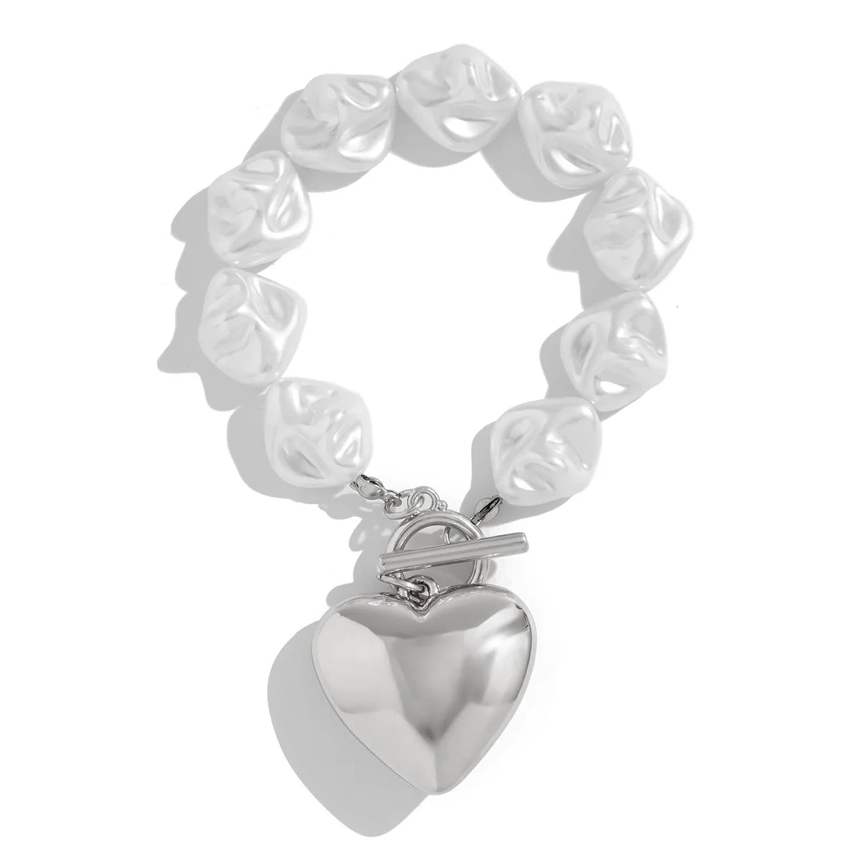 Silver toggle clasp bracelet with irregular pearl-like beads and large polished heart charm pendant on white background