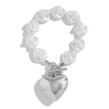 Silver toggle clasp bracelet with irregular pearl-like beads and large polished heart charm pendant on white background