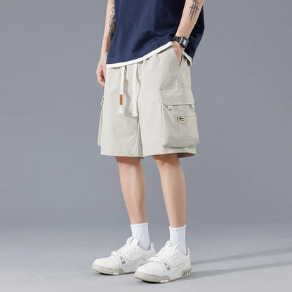 Men's beige cargo shorts with drawstring waist and side pockets, styled with navy tee and white sneakers