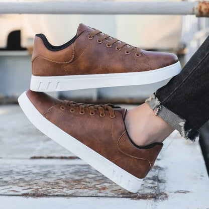Brown leather lace-up low-top men's sneakers with white rubber sole, worn with black distressed jeans