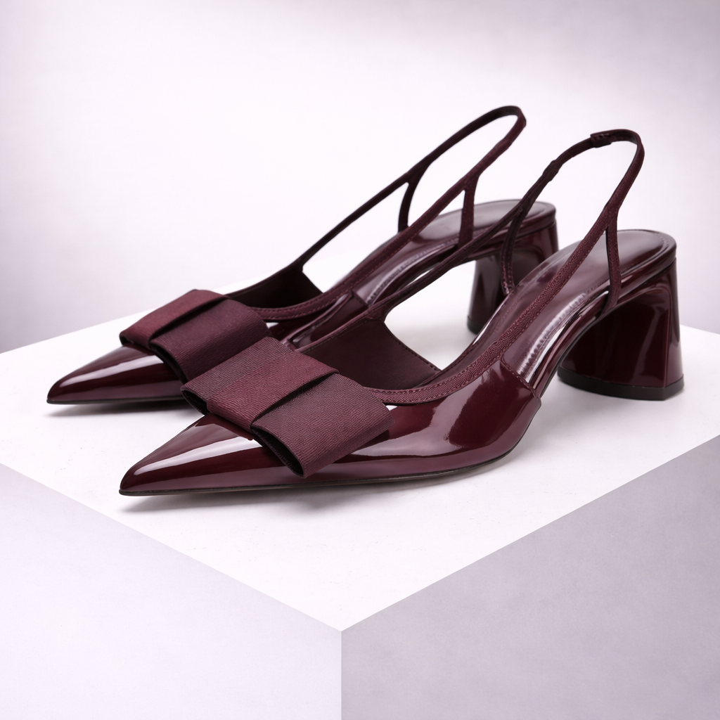 Women's burgundy pointed-toe patent leather slingback heels with bow detail and block heel on white display