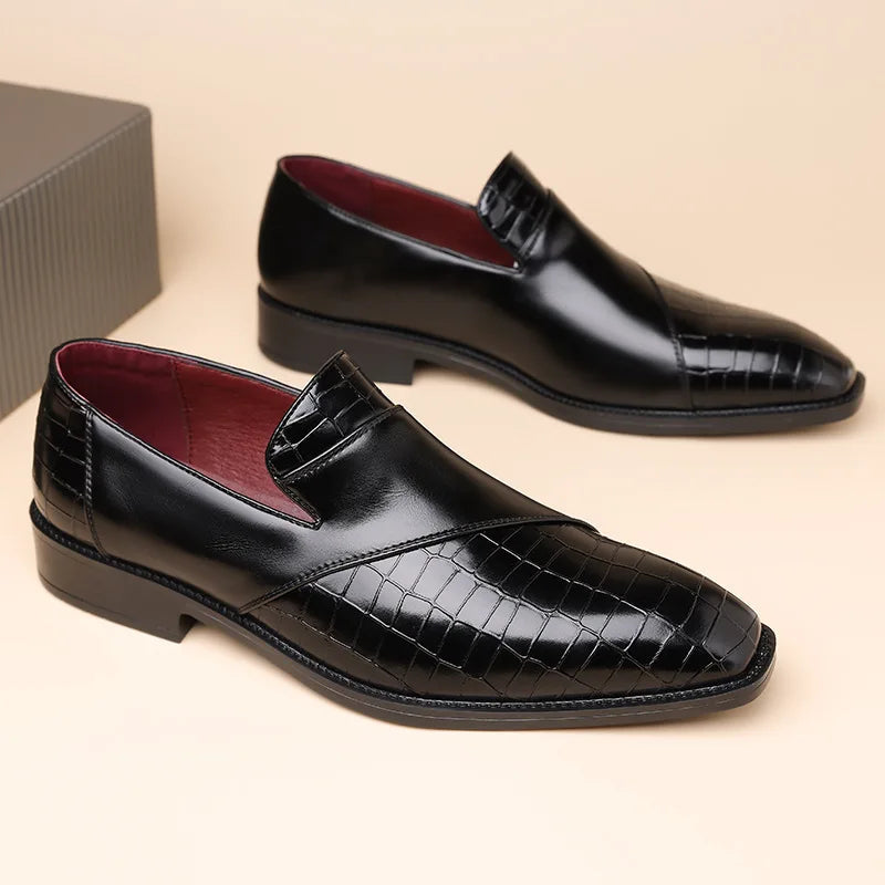 Black men's leather slip-on loafers with crocodile-embossed toe, smooth upper, burgundy lining, and low heel.