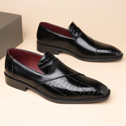 Black men's leather slip-on loafers with crocodile-embossed toe, smooth upper, burgundy lining, and low heel.