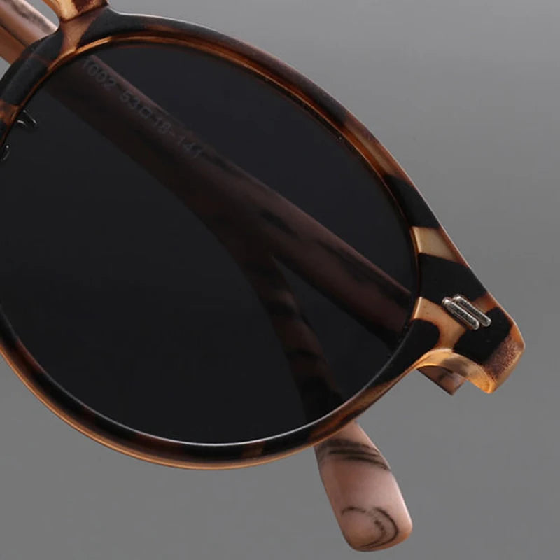 Close-up of round tortoiseshell sunglasses with dark tinted lenses and marbled brown acetate frame and temples