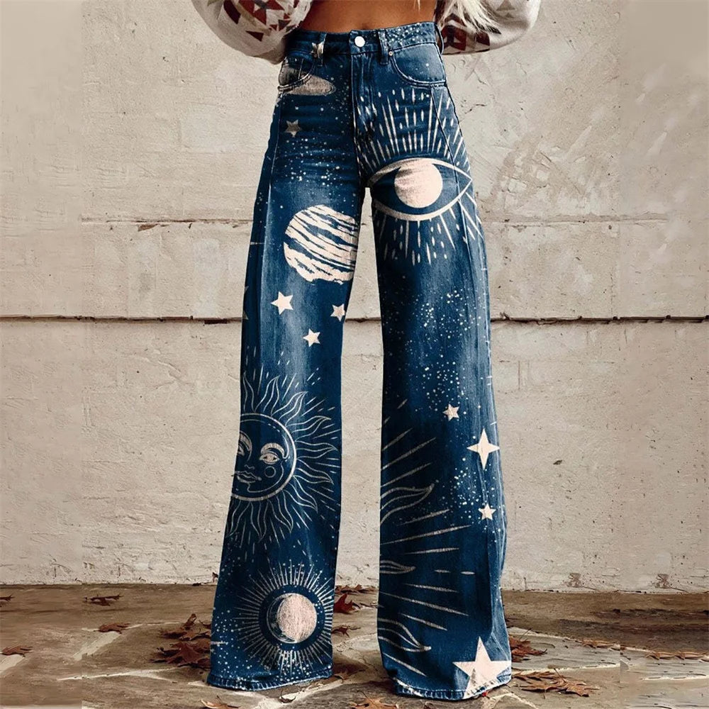 Women's high-waist wide-leg jeans featuring celestial sun, moon, stars, and planet prints on dark blue denim fabric.
