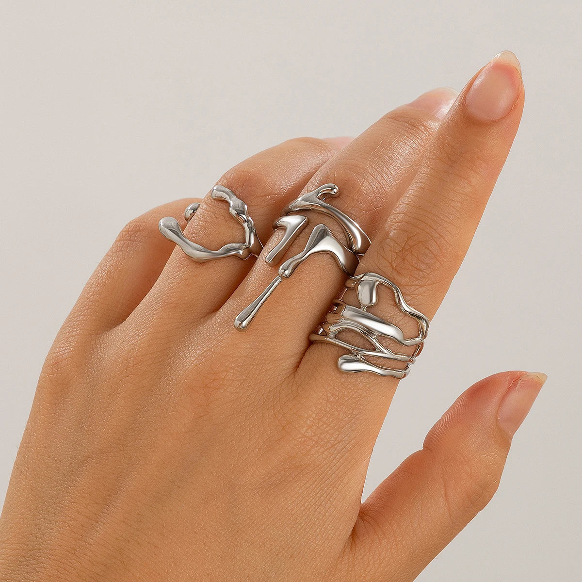 Silver adjustable molten drip ring set worn on hand, featuring abstract liquid metal design on multiple fingers