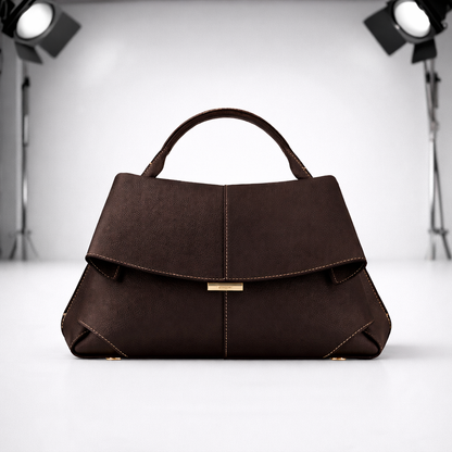 Dark brown structured leather handbag with top handle and gold accents on white studio background