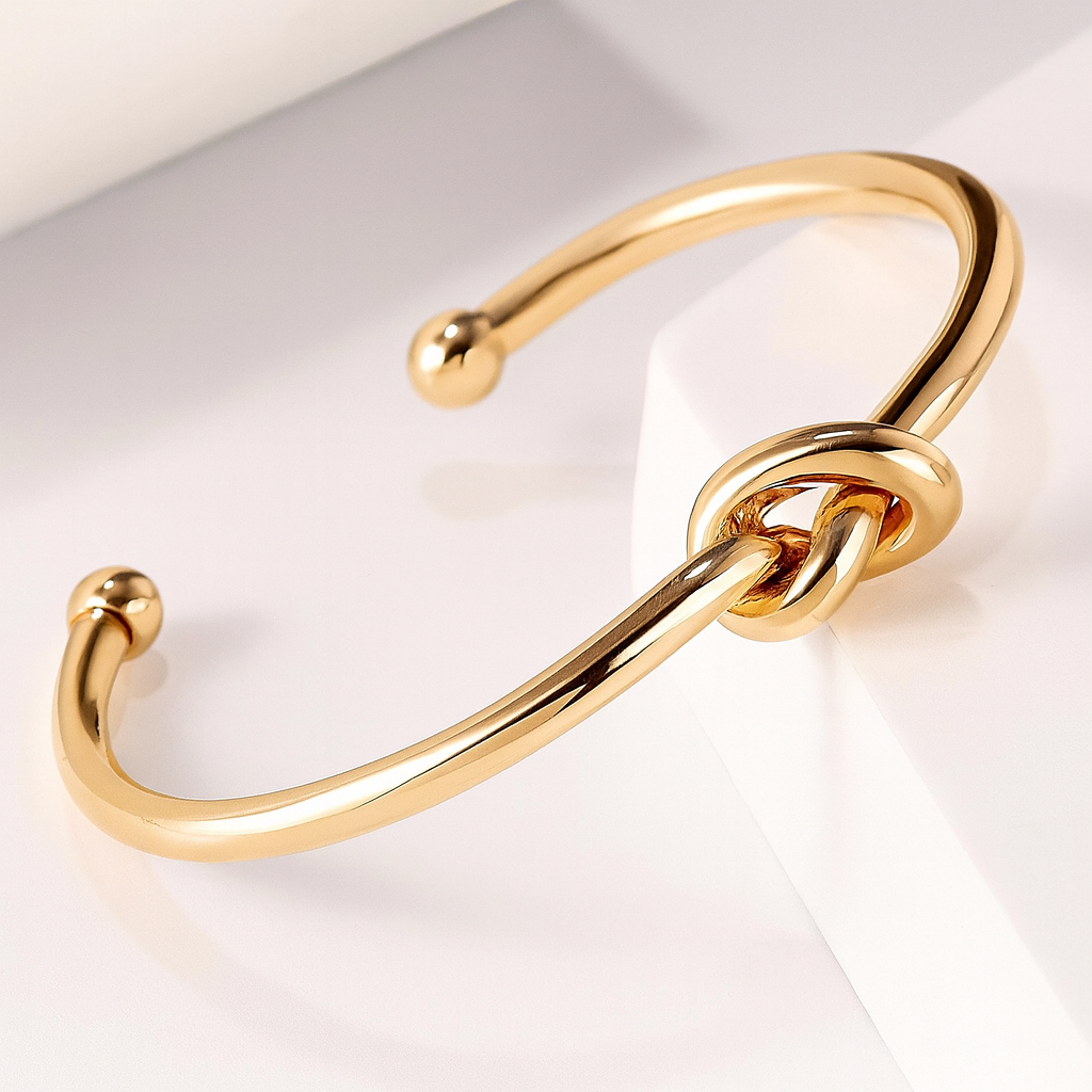 Gold knotted cuff bracelet for women with open ends and polished finish on white background