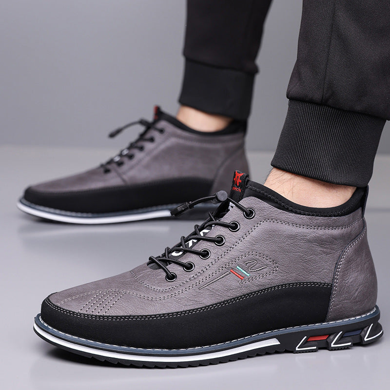 Gray leather mid-top men's sneakers with black laces, contrast sole, and color-accent details, worn with black joggers.