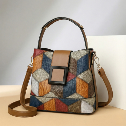 Multicolor patchwork leather bucket bag with top handle, brown shoulder strap, and black square buckle closure
