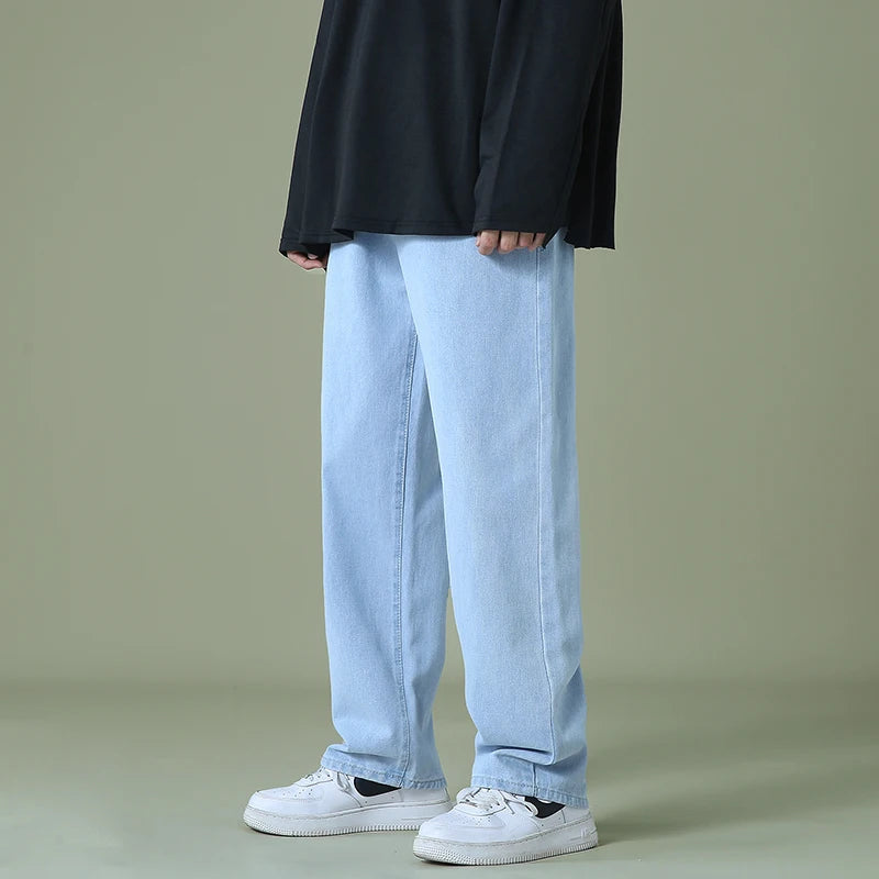 Light blue relaxed-fit denim jeans for men with straight leg cut and rolled cuffs worn with white sneakers