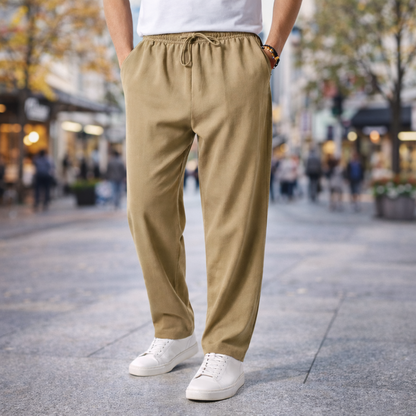 Man wearing khaki cotton drawstring pants with side pockets, paired with white sneakers and t-shirt, standing on city street.