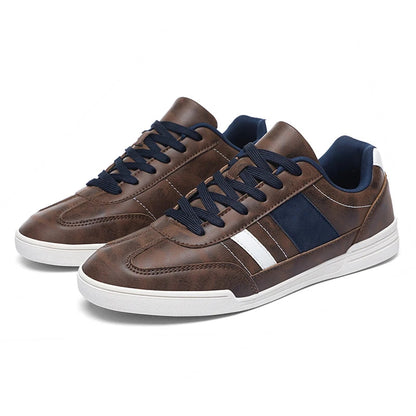 Brown leather low-top men's sneakers with navy blue laces, side stripe detailing, and white rubber sole