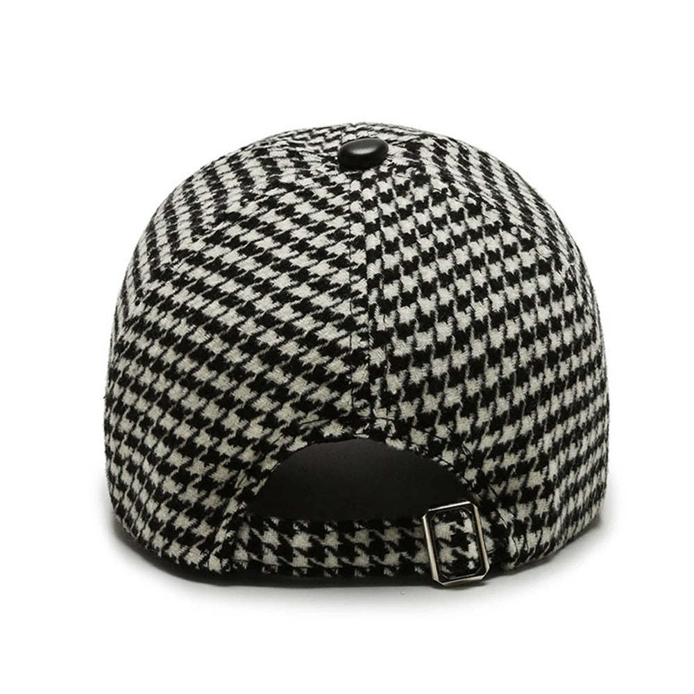 Back view of black and white houndstooth adjustable baseball cap with metal buckle closure and button top.