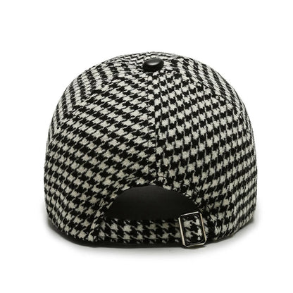Back view of black and white houndstooth adjustable baseball cap with metal buckle closure and button top.