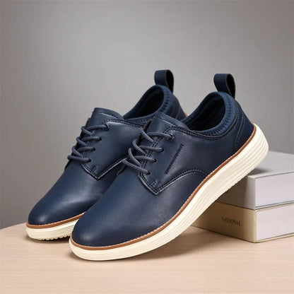 Navy blue men's leather lace-up casual Oxford shoes with white rubber sole, displayed on wooden surface with box.