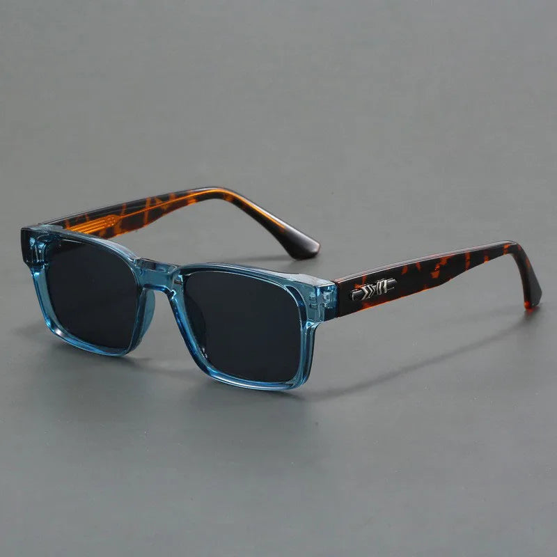 Square frame sunglasses with transparent blue front, tortoiseshell temples, dark lenses, and decorative metal hinge detail