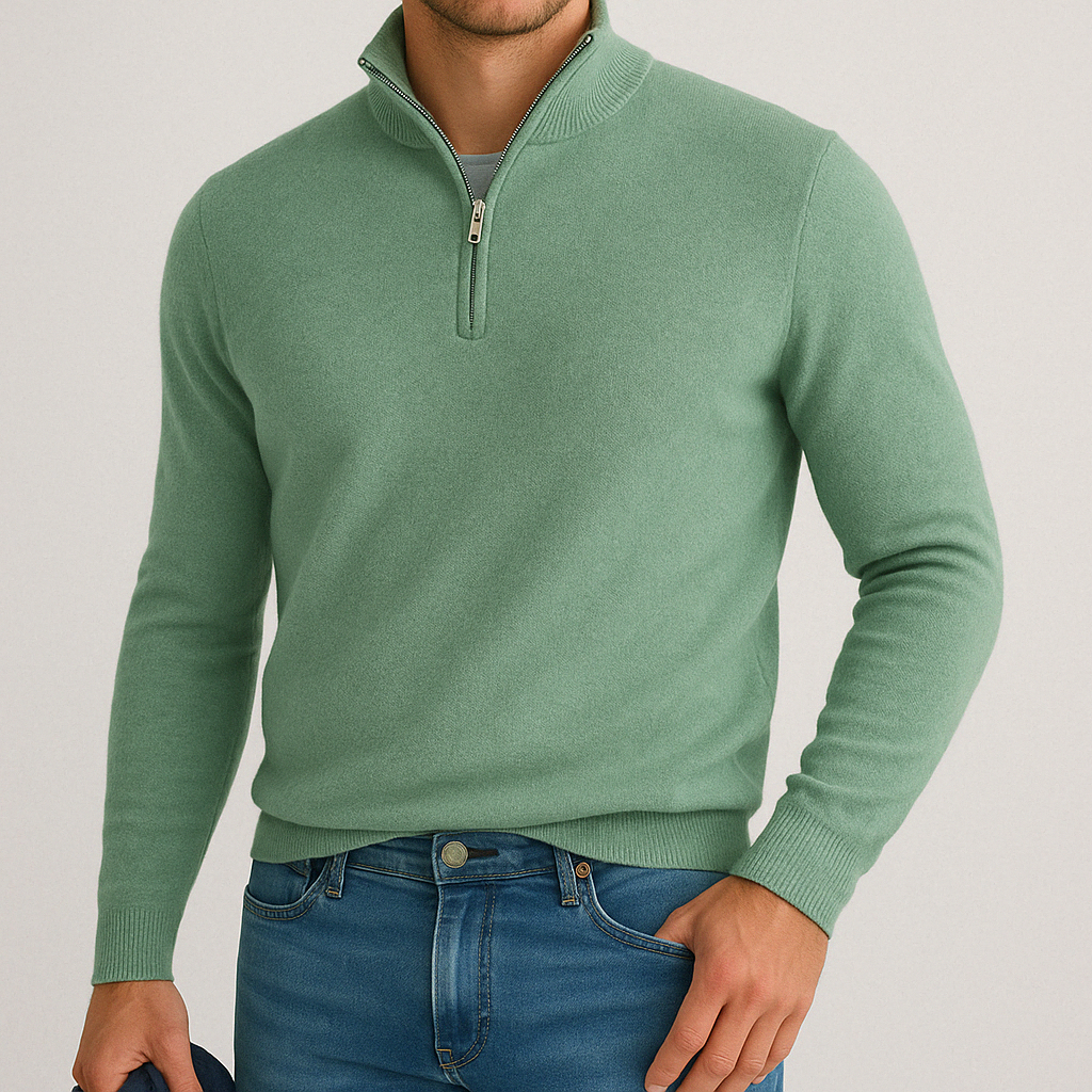 Man wearing a sage green cashmere blend quarter-zip sweater with ribbed cuffs and hem, paired with blue jeans.