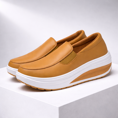 Women's tan leather slip-on platform sneakers with white curved rocker sole and elastic side panels