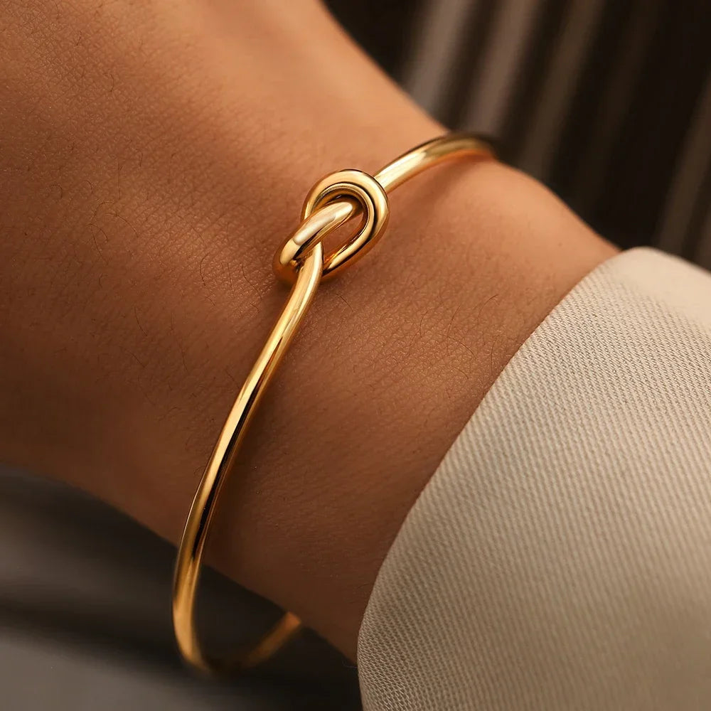 Gold knotted cuff bracelet on woman's wrist, elegant minimalist design jewelry accessory