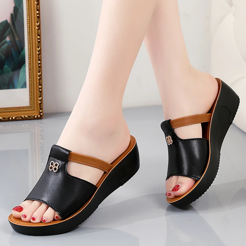 Black and tan platform slide sandals with cutout detail and wedge heel for women, red pedicure shown