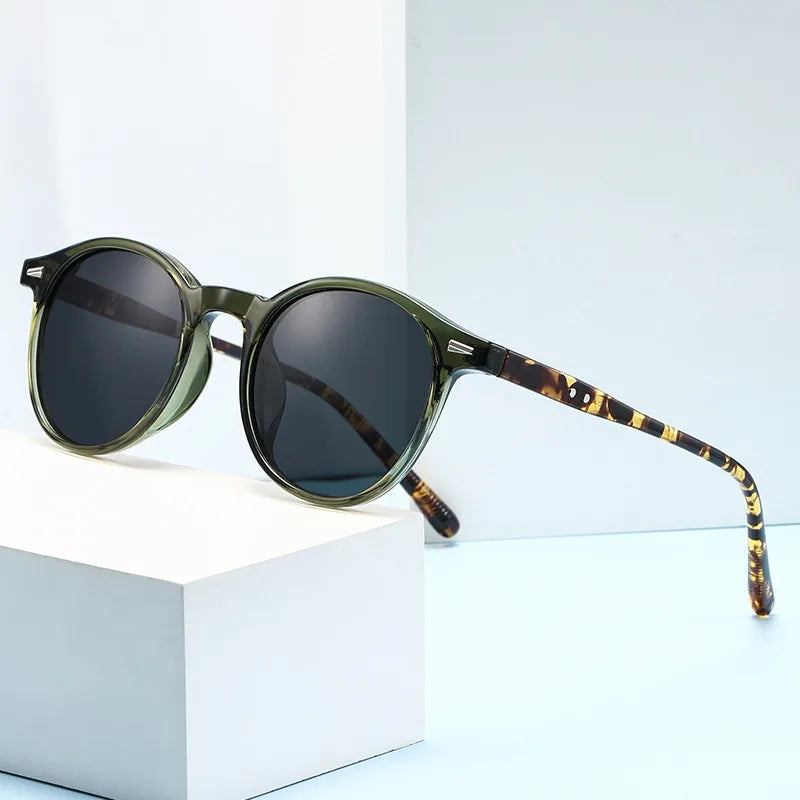 Round green acetate sunglasses with dark lenses and tortoiseshell pattern temples for women displayed on white blocks