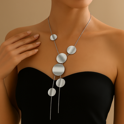 Asymmetric silver disc chain necklace with graduating circular pendants and tassel drop on black strapless top