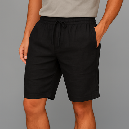 Men's black linen drawstring shorts with elastic waistband and side pockets, worn with a gray t-shirt.