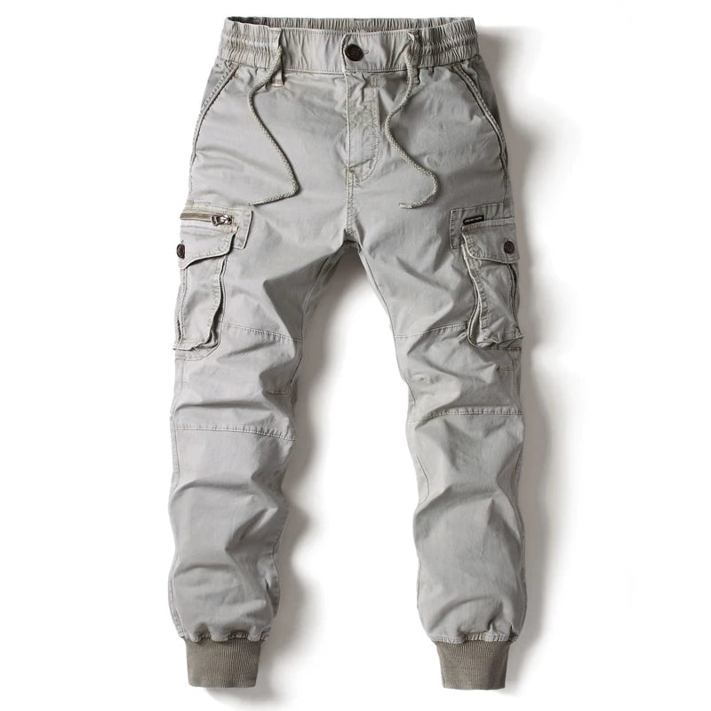 Light gray men's slim-fit cargo jogger pants with elastic waistband, drawstring, side zip and flap pockets, ribbed cuffs.