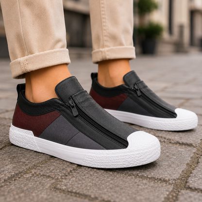 Women's leather slip-on sneakers with zipper closure, black and burgundy upper, white platform sole, worn with beige pants.