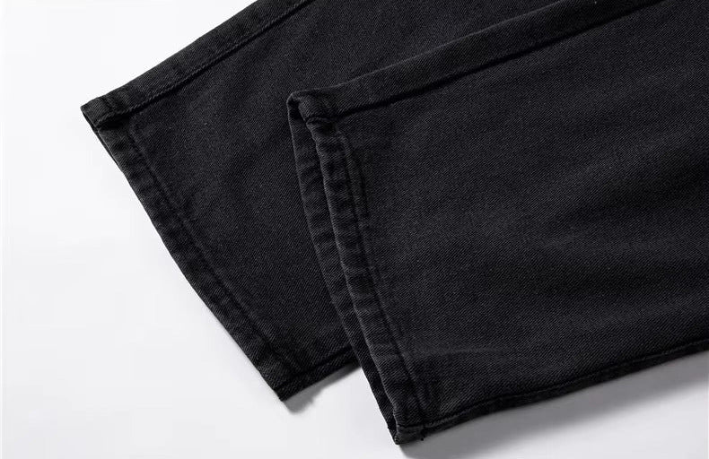 Close-up of black relaxed-fit men's denim jeans hem showing clean stitching and quality fabric construction.