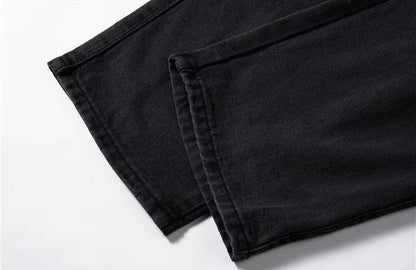 Close-up of black relaxed-fit men's denim jeans hem showing clean stitching and quality fabric construction.