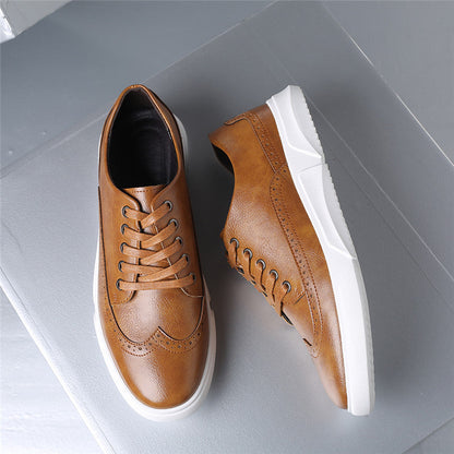Tan leather brogue lace-up sneakers with white rubber sole, displayed flat on gray surface, top and side view.