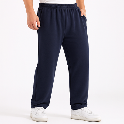 Navy blue men's cotton sweatpants with elastic waist and side pockets, paired with white sneakers, relaxed fit.
