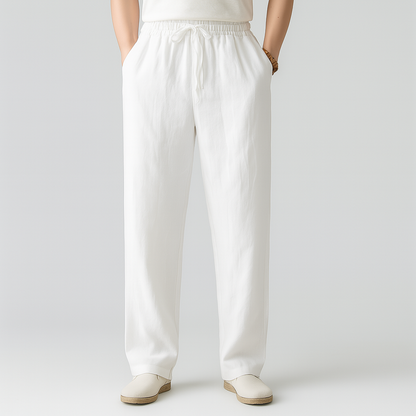Men's white linen drawstring pants with elastic waistband, relaxed straight fit, side pockets, paired with white slip-on shoes.