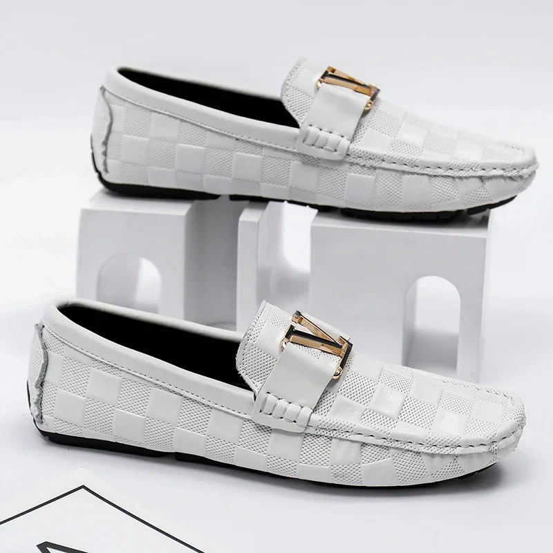 White checkered slip-on loafers for men with gold metal V-buckle detail and moccasin stitching, displayed on white blocks